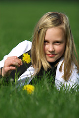 Image showing blonde girl smiling and lies in the grass with a flower