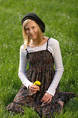 Image showing blonde girl smiling and lies in the grass with a flower