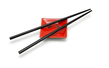 Image showing Chopsticks on  small red square saucer with kanji inscription isolated