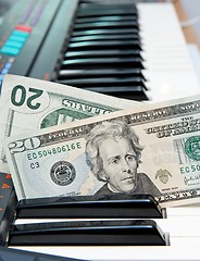 Image showing Two twenty dollar bills stuck in electric organ keyboard