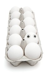 Image showing Funny egg with eyes among dozen in a paper box isolated