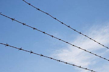 Image showing Three strands of rusty barbed wire over sky 