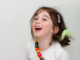 Image showing Laughing girl in white shirt with colored beads