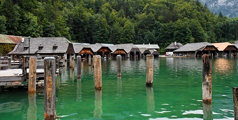 Image showing Wooden boat houses and mooring posts on green lake water
