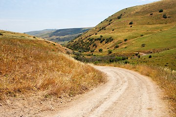Image showing Countryside road bends among yellow autumn hills 