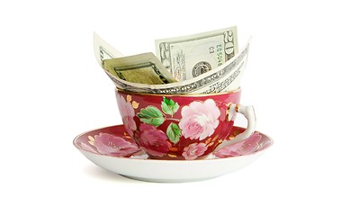 Image showing Tea cup with twenty dollar bills sticking out isolated 