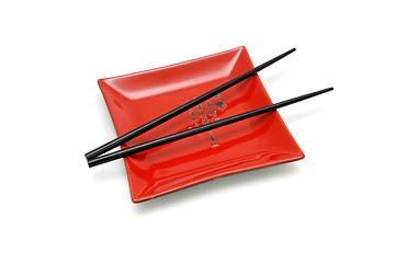 Image showing Chopsticks on red square plate with kanji inscription isolated