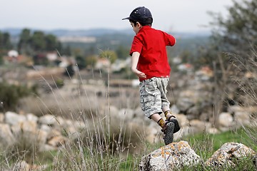 Image showing Little boy jumps from the stone outdoors
