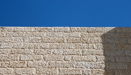 Image showing Beige rough stone wall and blue sky texture