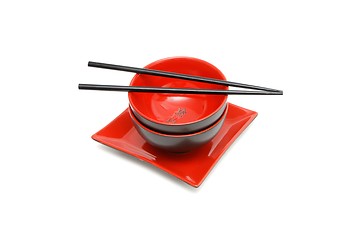 Image showing Black chopsticks on red and black Japanese bowl and square plate isolated