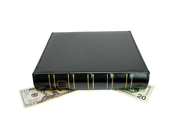 Image showing Thick black book on twenty dollar bills isolated