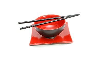 Image showing Chopsticks on red and black oriental bowl and square plate isolated