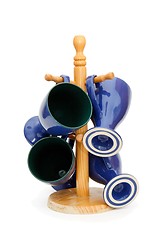 Image showing Four blue coffee cups hanging on wooden rack isolated