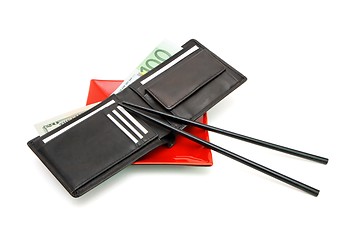 Image showing Black wallet with money on red square plate with chopsticks isolated