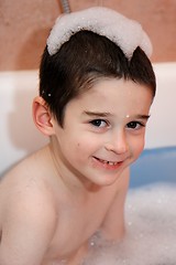 Image showing Cute little boy in a bathtub with foam cap on his head