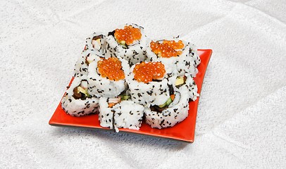 Image showing Homemade inside-out maki sushi with red caviar on red square plate 