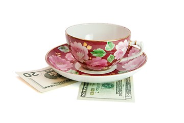 Image showing Tea cup and saucer on twenty dollar bills isolated