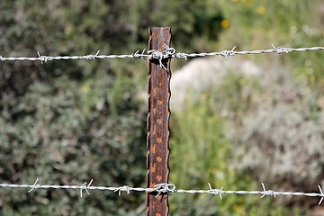 Image showing Two strands of barbed wire fence on rusty steel post
