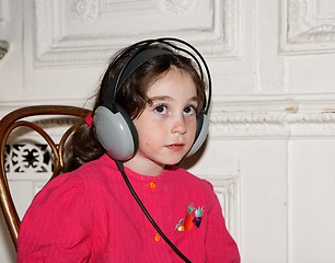 Image showing Cute little seven years girl listens to music in earphones