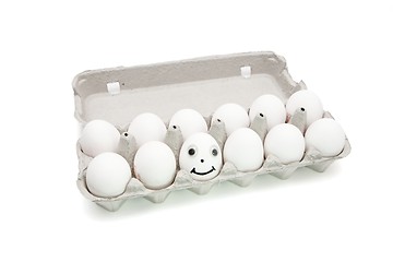 Image showing Funny egg with eyes among dozen in a paper box isolated