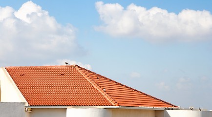 Image showing Orange tiled roof under the cloudy blue sky 