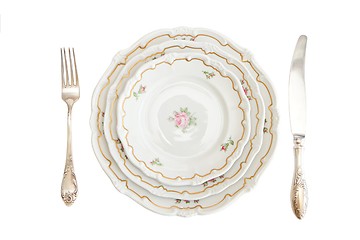 Image showing Dinner set with three plates, knife and fork isolated