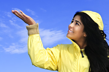 Image showing Beautiful young woman in raincoat checking for rain