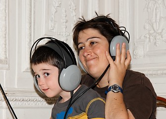 Image showing Cute little boy listens to music in earphones with his mother 