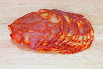 Image showing sliced salami on wooden plate