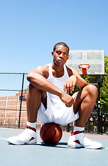 Image showing Basketball player sitting on ball