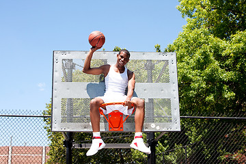 Image showing Champion basketball player sitting in hoop