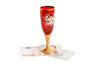Image showing Red wine glass  with golden stem on euro bills isolated