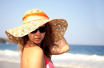 Image showing beautiful woman standing by the sea in a  hat 