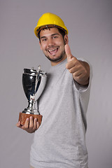 Image showing Smiling worker with big silver cup and thumb up