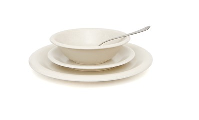 Image showing Beige soup, dinner plates and saucer with spoon isolated