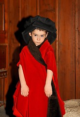 Image showing Serious cute little boy in medieval costume standing on wooden background