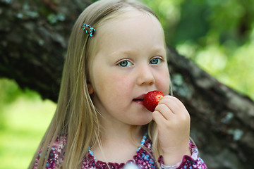 Image showing Happy little girl eating a strawberry. 