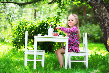 Image showing Smiling little girl holding a strawberry at tea party. 