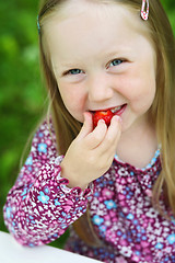 Image showing Smiling little girl eating a strawberry. 