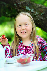Image showing Smiling little girl holding a strawberry at tea party.