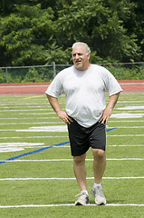 Image showing middle age man stretching and exercising on sports field