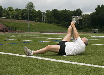 Image showing middle age man stretching and exercising on sports field