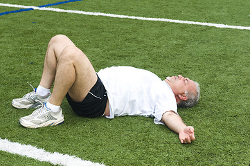 Image showing middle age man stretching and exercising on sports field