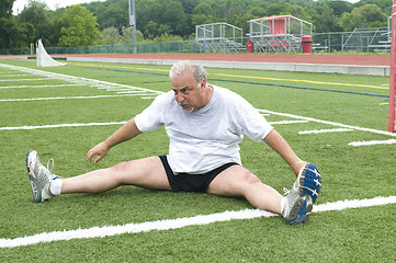 Image showing middle age man stretching and exercising on sports field