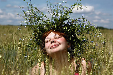 Image showing The smiling girl in a garland among the ears of the wheat