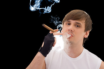 Image showing Young man smoking a cigar. Isolated on black