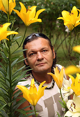 Image showing The man among yellow lilies