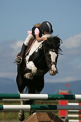 Image showing Rider and horse jumping fence