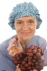Image showing nurse promoting healthy diet with fresh fruit grapes while weari