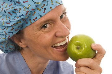 Image showing smiling happy nurse doctor eating green apple